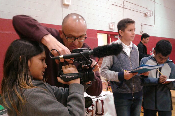 Photo of Professor Hugo showing a middle school student how to use a TV camera